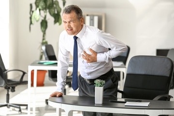 Mature man suffering from heart attack in office