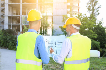 Architects discussing project of building outdoors