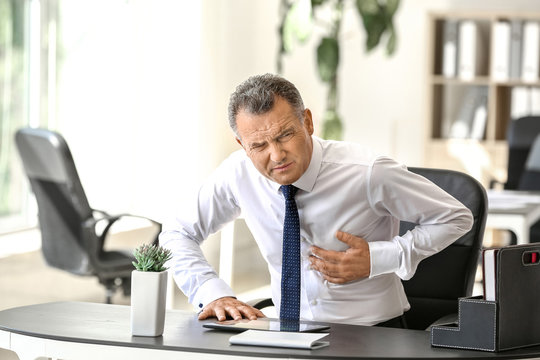 Mature man suffering from heart attack in office