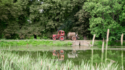 farmer pumping water from river. water tank full of water for farming. blurred wild grasses. landscape background.