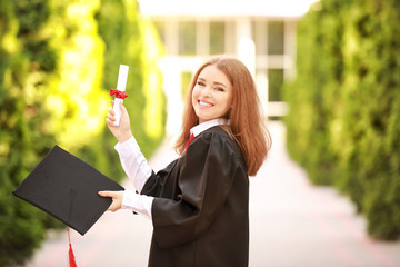 Happy young woman with diploma on graduation day