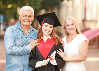 Happy young woman with her parents on graduation day
