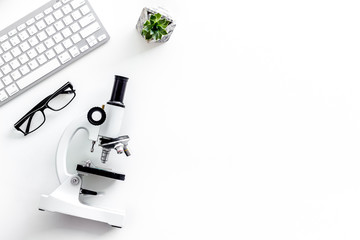 Laboratory desk with keyboard and microscope on white background top view space for text