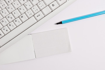 White pc keyboard with empty note paper above white background.