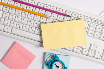 Flat lay above empty note paper on the pc keyboard pencils and clock.