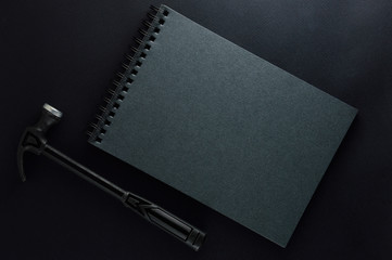 Isolated black hammer and black gray note book on black matte background