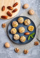Energy ball cakes with dried apricots, sesame, linen, walnuts and dates on a gray concrete  background, top view, close up.