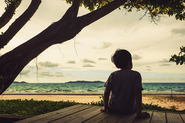 child sitting and looking at the beach
