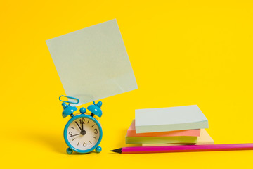 Alarm clock blank pencil sticky note stacked notepads colored background