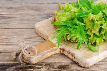 Green mix of different leaves on wooden board, vegetarian food, diet