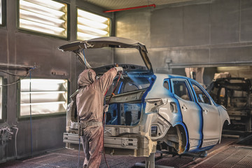 Employee car body painting shop carries out painting of the internal elements of the car