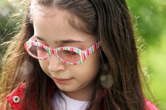 close up outdoor portrait of elementary age girl in sunny green garden
