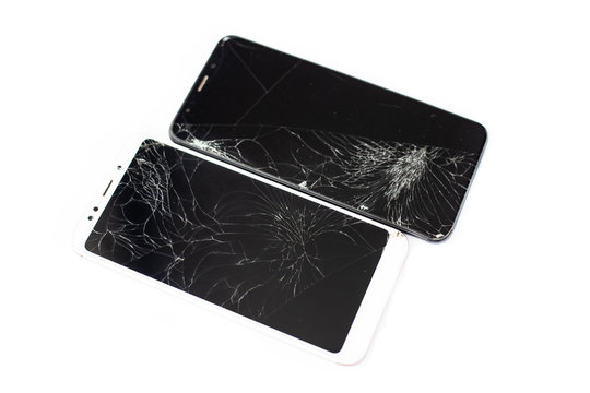two broken phones of white and black on a white background. cracked touchscreen glass of the touch screen isolate