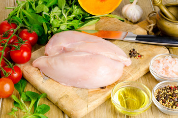 Fresh raw chicken fillet and vegetables prepared for cooking. 