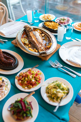 Turkish or Greek restaurant table and food dinner cuisine culture from top view. Traditional Greek ouzo or turkish raki with grilled or fried fish and appetizers on dinner table at restaurant. 