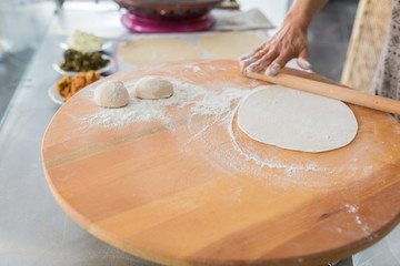 Woman preparing or making borek or bread dough. Hands keep rolling pin on dough with flour. Borek,...