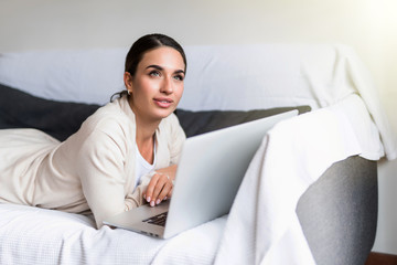 Young woman oman using a laptop while relaxing on the couch