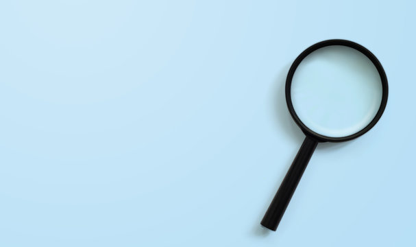 Magnifying glass on blue colour background with copy space. Searching information data concept
