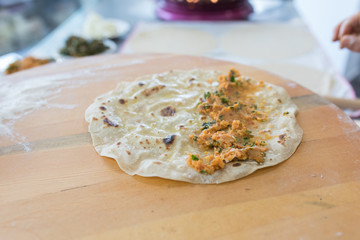 Preparing or making borek or bread dough. Hands keep rolling pin on dough with flour. Borek, bread or pastry dough on a wooden table background. Traditional Turkish pide, pita or yufka bread.