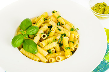 Penne pasta with spinach basil pesto sauce on white plate.