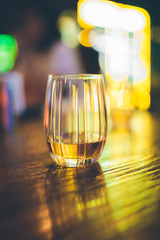 Single glass of whisky or whiskey on wooden table at pub, bar or restaurant at night. Scotch, bourbon or irish whiskey on wooden table. Nightlife concept image
