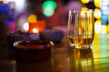 Single glass of whisky or whiskey on wooden table at pub, bar or restaurant at night. Scotch, bourbon or irish whiskey on wooden table. Nightlife concept image