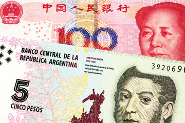 A five peso bill from Argentina, close up in macro with a red, one hundred yuan Chinese renminbi bank note