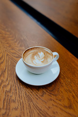 A cup of delicious latte coffee on wooden table background. Beautiful latte or cappuccino beverage art.
