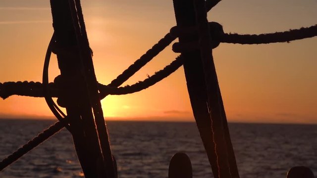 Sunset through the shrouds and rigging of an old sailing vessel.