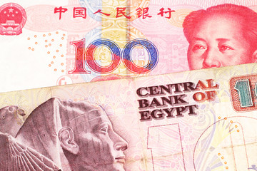 A ten Egyptian pound bill with a red, one hundred yuan Chinese renminbi note close up in macro