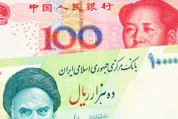 A close up image of a green Iranian ten thousand rial bank note with a red, one hundred yuan Chinese renminbi note in macro