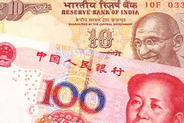 An orange, Indian ten rupee bill, close up with a red, one hundred yuan Chinese renminbi note