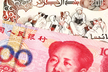 A beige, two hundred Algerian dinar bill with a red, Chinese renminbi one hundred yuan bank note close up in macro