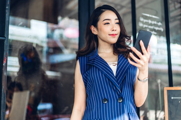 Businesswoman working and using mobile phone while standing in front of cafe