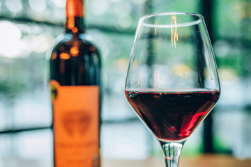 Glass of red wine and bottle of wine on wooden table