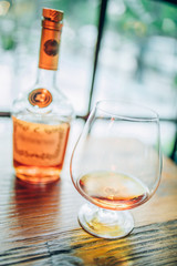 glass of whiskey or cognac and bottle on wooden table