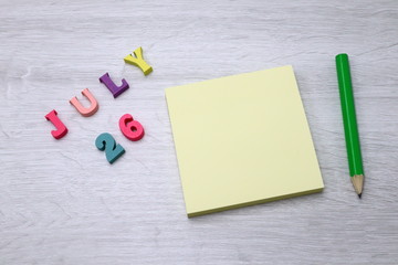 July 26 - Daily colorful Calendar with Block Notes and Pencil on wood table background, empty space for your text or design