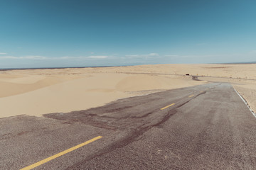 a road in the middle of the sand dunes in the desert.