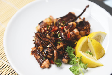 Octopus salad with lemon herbs and spices on white plate - Tentacles squid grilled appetizer food hot and spicy chilli sauce seafood cooked served