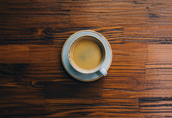 Cup of espresso or cappuccino coffee beverage on wooden table in cafe. 