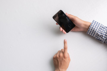 hands holding empty blank black smartphone on a white surface, mockup copy space