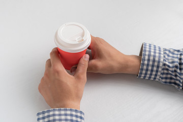 top view of hands holding a take away paper coffee cup