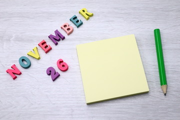 November 26 - Daily colorful Calendar with Block Notes and Pencil on wood table background, empty space for your text or design