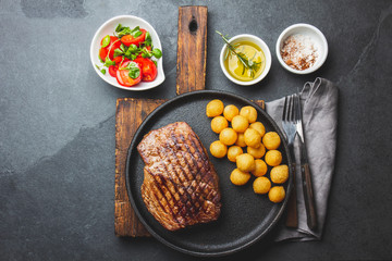 Grilled beef steaks with spices on black plate