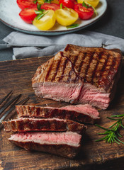Grilled beef steaks with spices on wooden cutting board