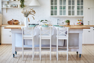 Beautiful white wooden kitchen with island table and chairs.