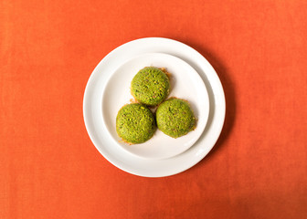 Turkish dessert kadayif with pistacchio on it. Also known antep kadayif in plate on orange background from top view