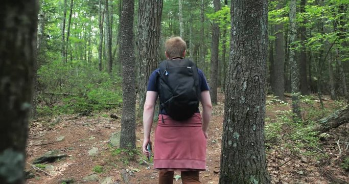 Stabilized footage of male hiking through green forest trail. 4K