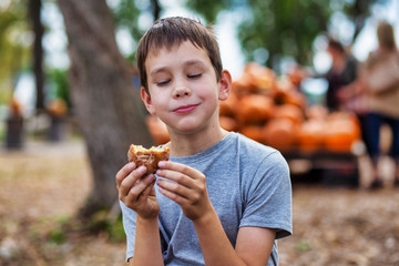 boy eating cider donut at the farm. the concept of harvest festival on the farm
