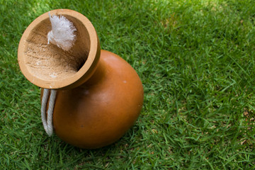 Hawaiian instrument, ipu, a carved, hollowed out gourd, on grass. In modern times it is used to keep the beat for hula dancing. It has also been used for food medicine and decoration.